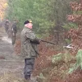 Myśliwi w lesie, w jakiej odległości od zabudowań mogą polować? Widać ich na ścieżce, wśród drzew.