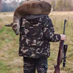 Myśliwy w kamuflażu niesie na ramionach upolowaną sarnę, trzymając sztucer. Czy myśliwy niestowarzyszony może polować?