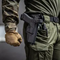 Czy myśliwy może nosić broń w miejscu publicznym? Na zdjęciu widać mężczyznę w mundurze z kaburą na pistolet.