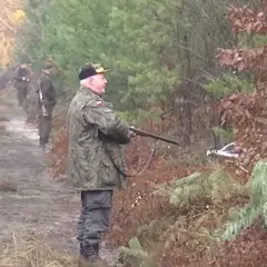 Myśliwi w lesie, w jakiej odległości od zabudowań mogą polować? Widać ich na ścieżce, wśród drzew.