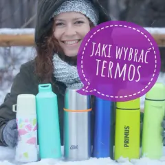 Kobieta w zimowym ubraniu trzyma kilka kolorowych termosów na śniegu.