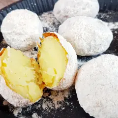 Ziemniaki pieczone w popiele, jeden przekrojony na pół, ukazujący miękki środek.
