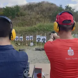 Na strzelnicy, gdzie nauka celowania jest jak lekcja w szkole, dwóch mężczyzn ćwiczy strzelanie.