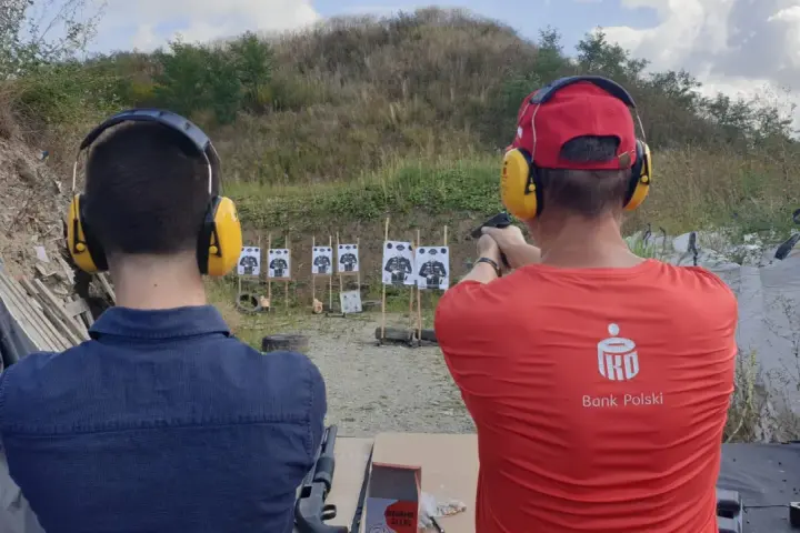 Na strzelnicy, gdzie nauka celowania jest jak lekcja w szkole, dwóch mężczyzn ćwiczy strzelanie.