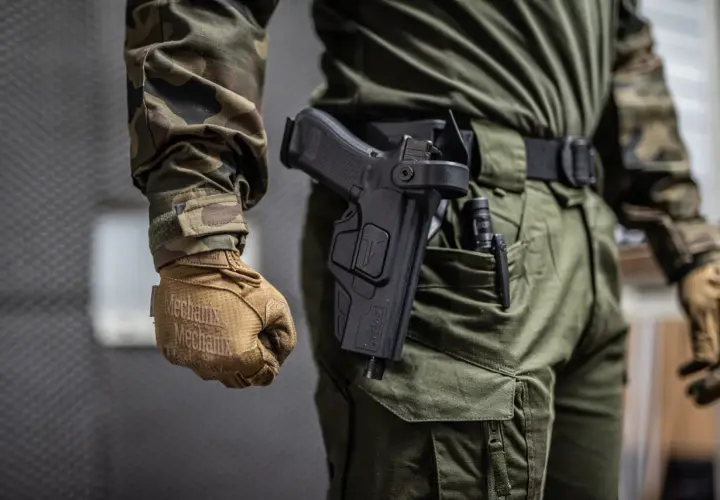 Czy myśliwy może nosić broń w miejscu publicznym? Na zdjęciu widać mężczyznę w mundurze z kaburą na pistolet.