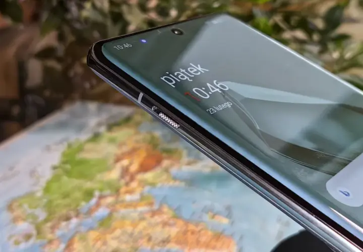 Zbliżenie na ekran telefonu z widocznym zegarem i mapą w tle.