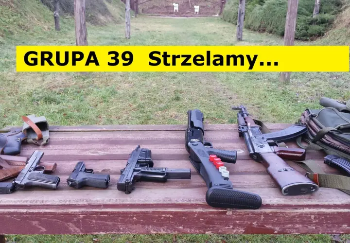 Na drewnianym stole leżą różne rodzaje broni palnej, w tle strzelnica.