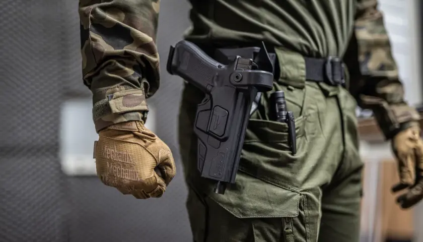 Czy myśliwy może nosić broń w miejscu publicznym? Na zdjęciu widać mężczyznę w mundurze z kaburą na pistolet.