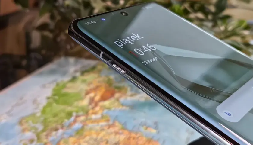 Zbliżenie na ekran telefonu z widocznym zegarem i mapą w tle.