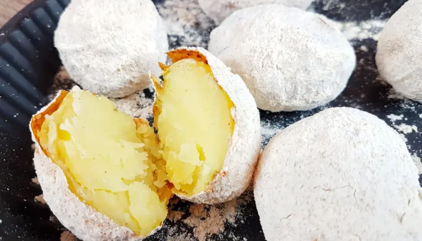 Ziemniaki pieczone w popiele, jeden przekrojony na pół, ukazujący miękki środek.