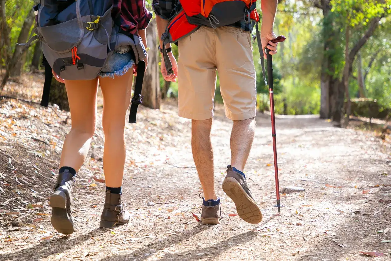 osoba używająca kij&oacute;w trekkingowych w g&oacute;rach z prawidłową postawą