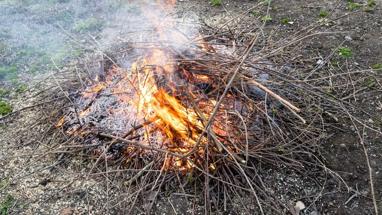 Osoba rozpalająca ognisko w deszczu pod osłoną